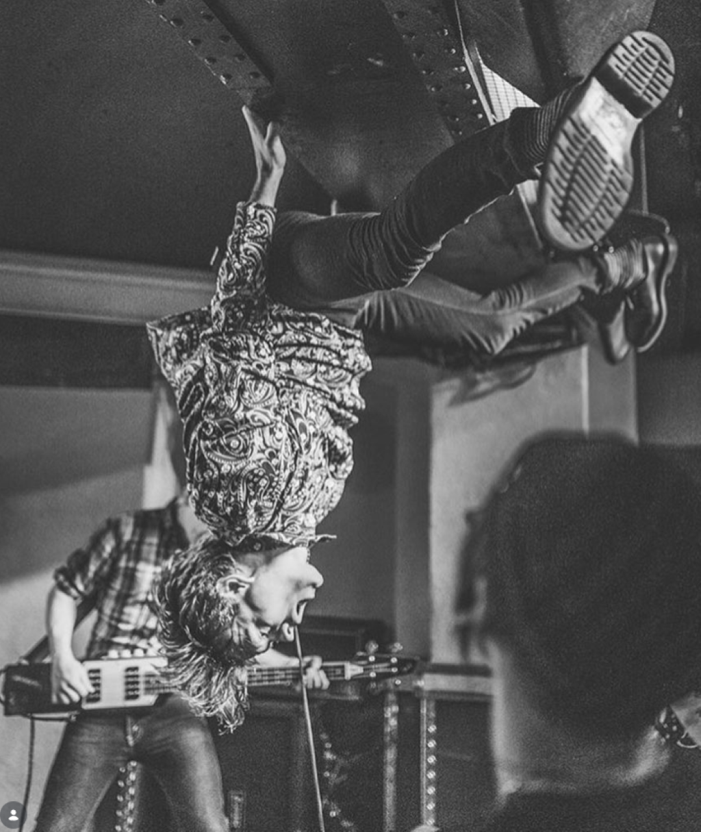 Punk performer hanging upside down on stage